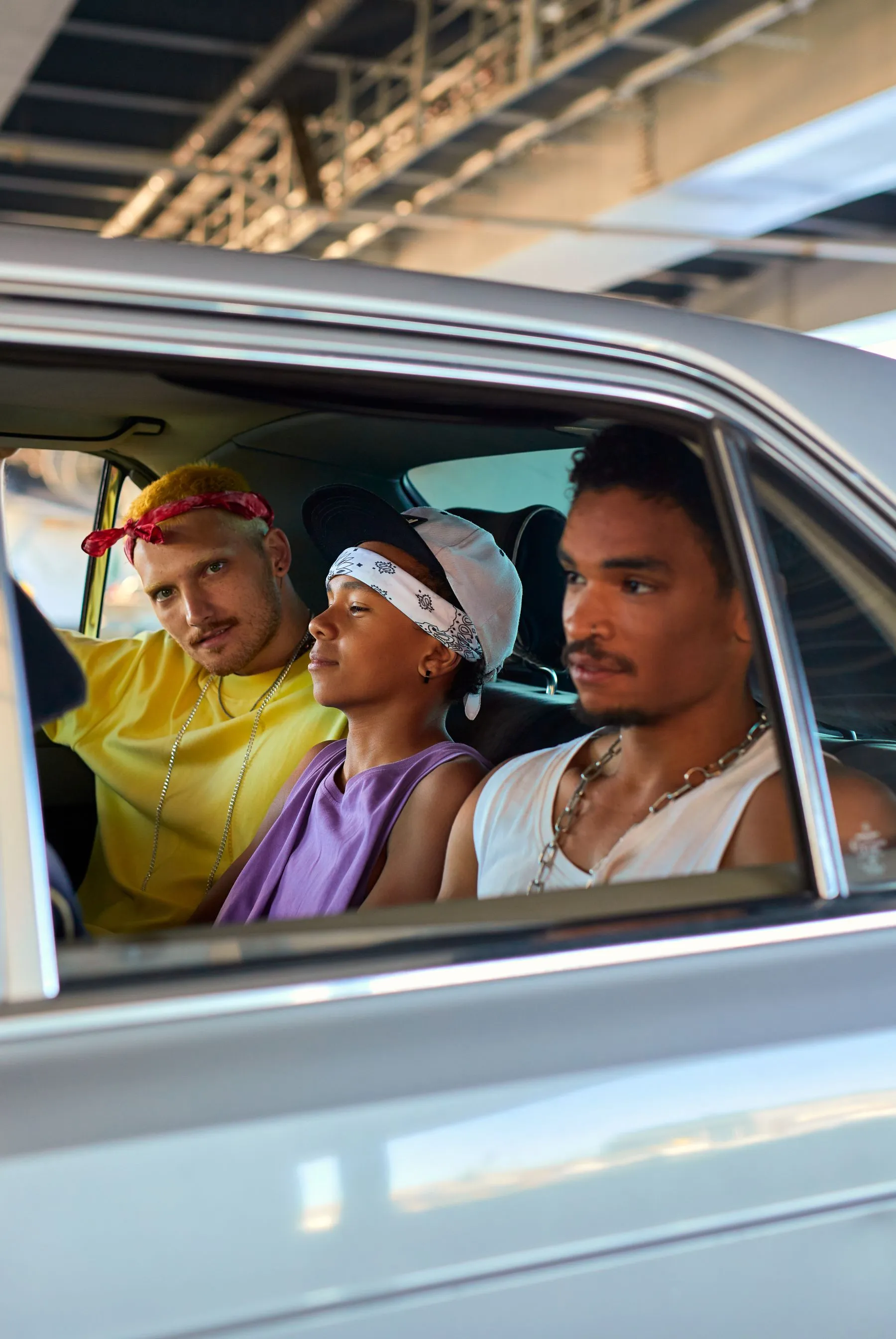 Three friends travelling together in a shared car, smiling through the open window