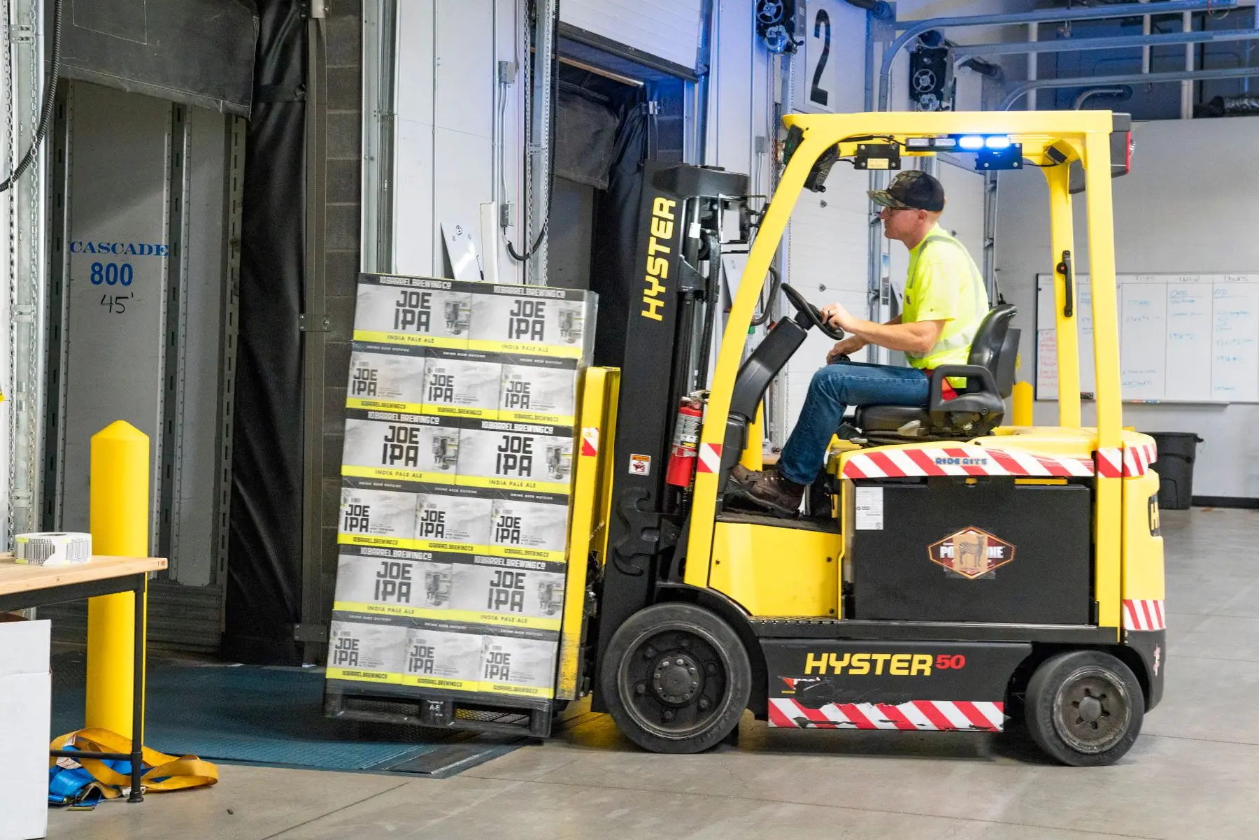 A forklift loading pallets at a warehouse dock for a business consignment